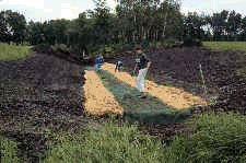 Installing erosion control matting to create a lined channel.
