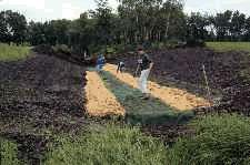 Installing erosion control matting to create a lined channel. 