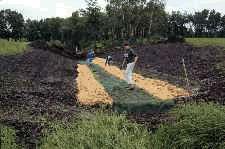 Installing erosion control matting to create a lined channel.